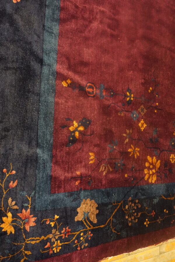 Plush burgundy field rug with delicate golden florals bordering a dark navy and teal edge.