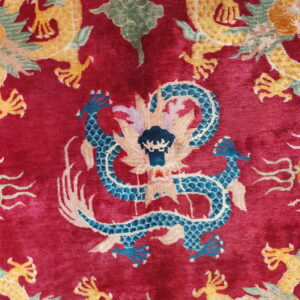 Close-up of a red plush rug with ornate blue, yellow, and green dragon patterns.