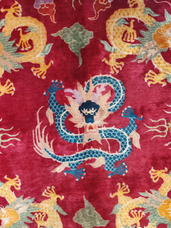 Close-up of a red plush rug with ornate blue, yellow, and green dragon patterns.