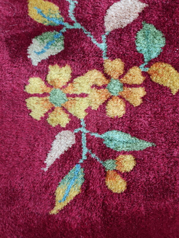 Plush burgundy rug with a detailed floral design featuring yellow, green, cream, and blue accents.