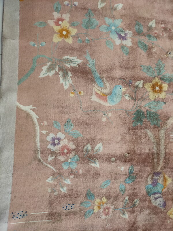 Red knotted antique 1920s room size wool rectangle chinese - art deco rug 3 Distressed dusty rose rug featuring multicolored flowers, vines, and a light blue bird pattern.