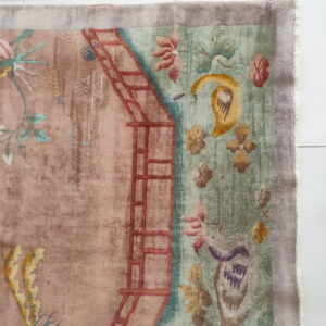 High-pile pictorial rug featuring botanical and trellis patterns in muted pink, sage, and gold on white tile.