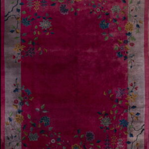 Deep magenta rug with a taupe border featuring multicolored floral and vine motifs framing the center field.