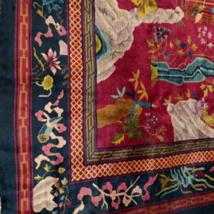 Plush pink and blue rug displaying a detailed scenic design and various geometric border motifs.