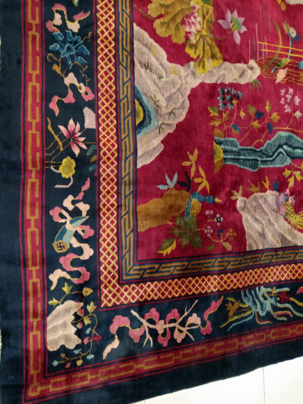 Plush pink and blue rug displaying a detailed scenic design and various geometric border motifs.