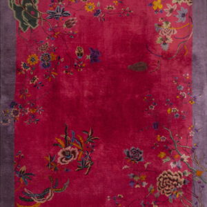 Bright pink rug featuring detailed multicolored florals and vines surrounding the field, framed by a purple border.