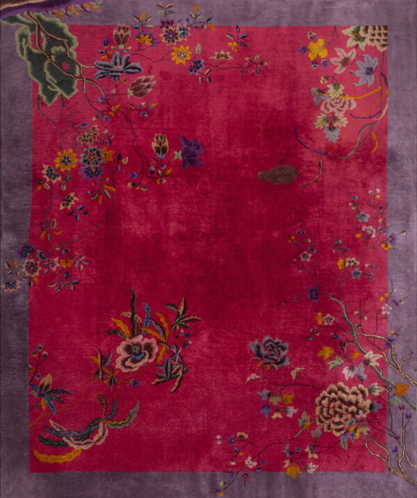 Bright pink rug featuring detailed multicolored florals and vines surrounding the field, framed by a purple border.