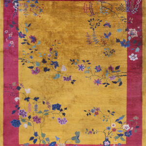 Golden yellow rug with a magenta border featuring multicolored floral and vine motifs.