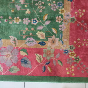 Multicolor floral rug with contrasting fields of green and pink, separated by a gold stripe border.