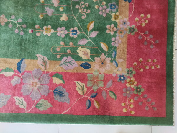 Multicolor floral rug with contrasting fields of green and pink, separated by a gold stripe border.
