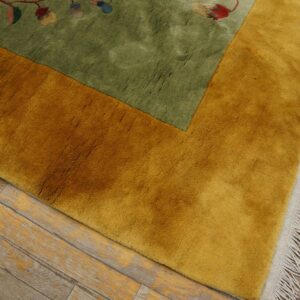 Green and gold high-pile rug featuring a floral pattern, set on weathered wood plank flooring.