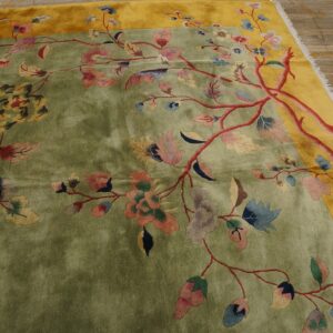Low-pile rug in green and yellow with a large-scale, colorful floral vine pattern on wood planks.