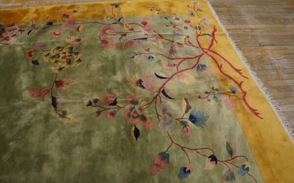 Low-pile rug in green and yellow with a large-scale, colorful floral vine pattern on wood planks.