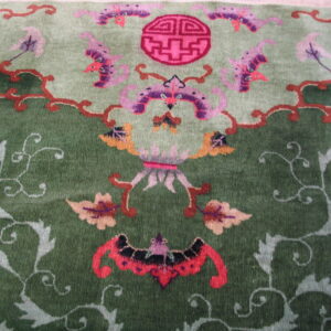 Green high-pile rug with stylized pink, purple, and orange floral and figurative motifs.