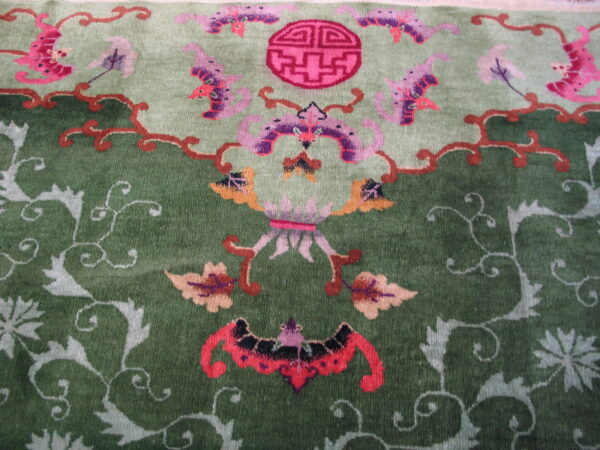 Green high-pile rug with stylized pink, purple, and orange floral and figurative motifs.