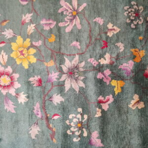 High-pile teal rug featuring a detailed floral pattern with pink, yellow, and white blossoms.
