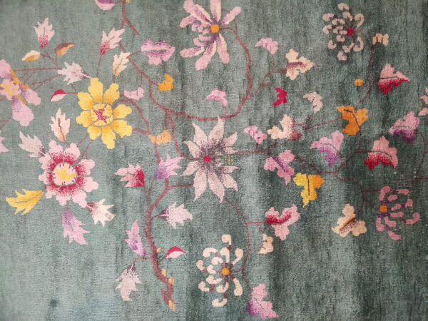 High-pile teal rug featuring a detailed floral pattern with pink, yellow, and white blossoms.