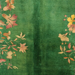 Plush green rug with a lustrous texture and intricate botanical patterns in yellow, gold, and rose.