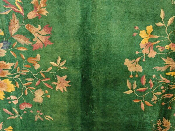 Plush green rug with a lustrous texture and intricate botanical patterns in yellow, gold, and rose.