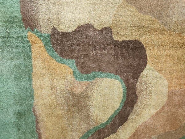 Textured, mid-pile rug detail showing wavy abstract shapes in brown, tan, and seafoam green colors.