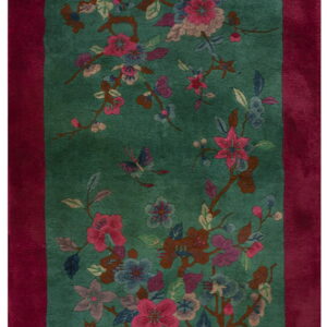 Teal field rug with a wide magenta border and a floral pattern including pink blossoms and butterflies.