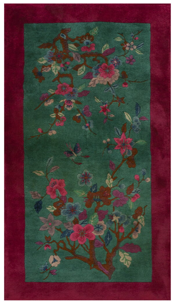 Teal field rug with a wide magenta border and a floral pattern including pink blossoms and butterflies.