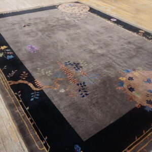 Dark taupe rug featuring colorful botanical designs, black borders, and light wood plank flooring.
