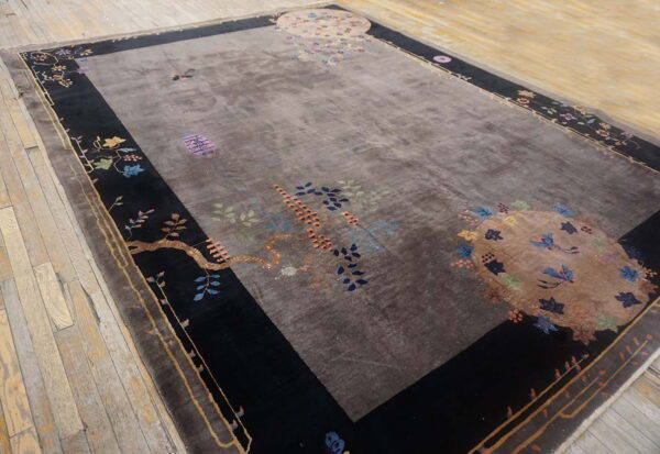 Dark taupe rug featuring colorful botanical designs, black borders, and light wood plank flooring.