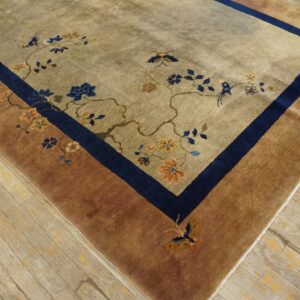 Beige rug featuring blue and orange floral branches, birds, and butterflies, bordered in navy and reddish-brown.