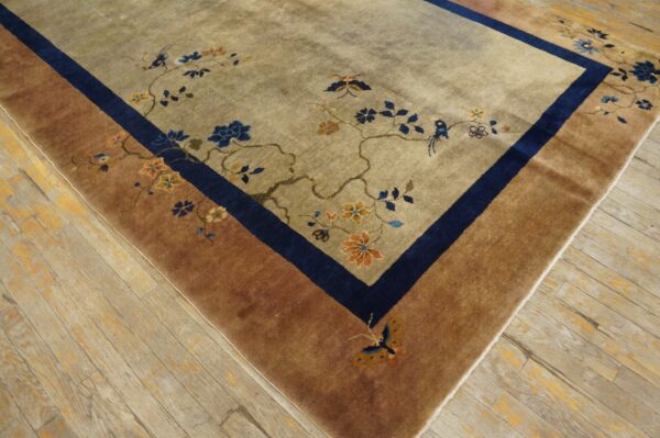 Beige rug featuring blue and orange floral branches, birds, and butterflies, bordered in navy and reddish-brown.
