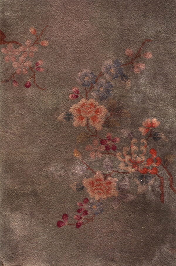 Muted low-pile rug with a distressed dark brown field and faded floral motifs in pink, blue, and rust.