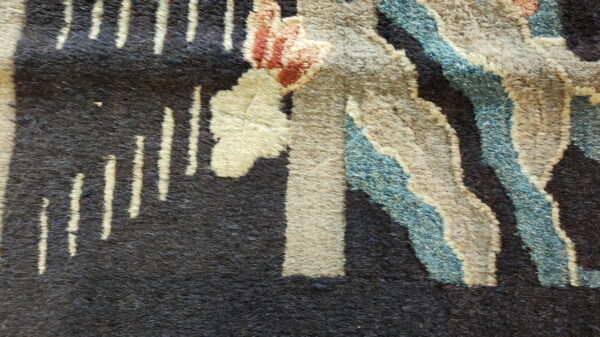Close-up of a textured rug with abstract shapes in dark brown, cream, blue, and reddish-brown.