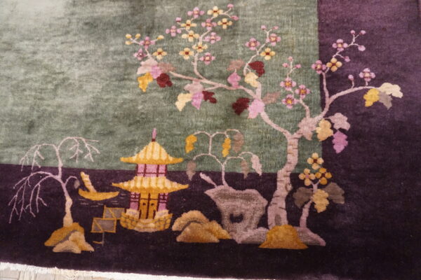 Scenic detail of a plush rug showing a gold pagoda and pink flowering trees on sage and purple.