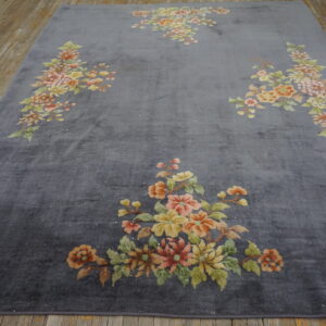 Low-sheen gray rug with bouquets of yellow, pink, and green flowers lying on wooden plank flooring.