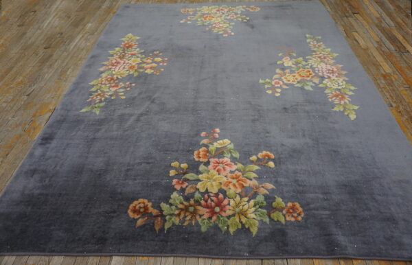 Low-sheen gray rug with bouquets of yellow, pink, and green flowers lying on wooden plank flooring.