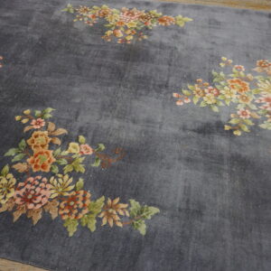 Plush dark grey rug displays corner bouquets of orange, pink, and green flowers on wood flooring.