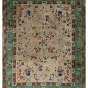 Beige rug with colorful floral motifs, birds, and vases, bordered by intricate teal and magenta patterns.