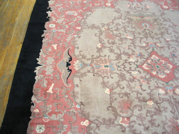 Muted traditional rug in pink, gray, and black on a light brown wood floor.