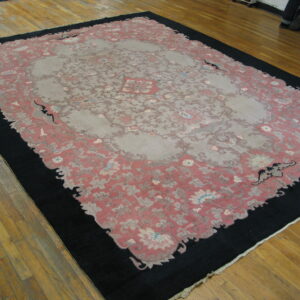 Large low pile rug with a gray central medallion, dusty rose field, and wide black border.