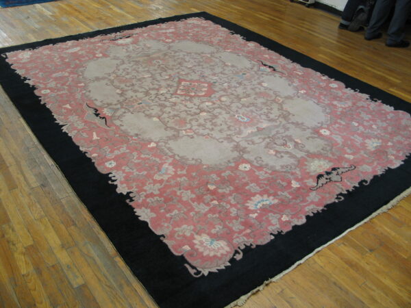 Large low pile rug with a gray central medallion, dusty rose field, and wide black border.