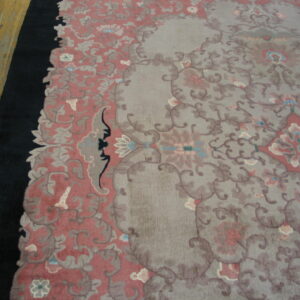 Low pile rug featuring a floral design in muted gray, dusty rose, and taupe next to hardwood floors.