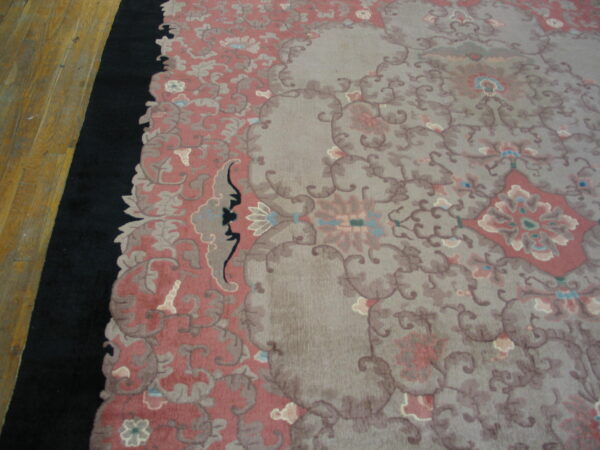 Low pile rug featuring a floral design in muted gray, dusty rose, and taupe next to hardwood floors.