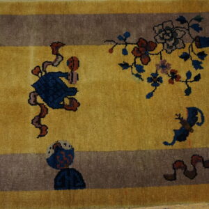 Gold rug with a wide taupe border featuring stylized blue, red, and brown figures and floral patterns.