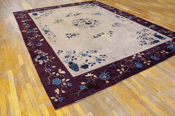 Light gray rug featuring blue floral sprays and a wide, deep purple patterned border on wood floors.