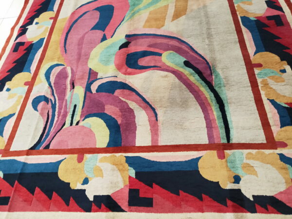 Multicolored rug with a swirling, abstract central motif and a bold geometric border.