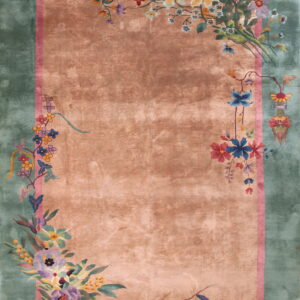 Plush coral rug with green borders featuring bright floral designs and trailing vines.