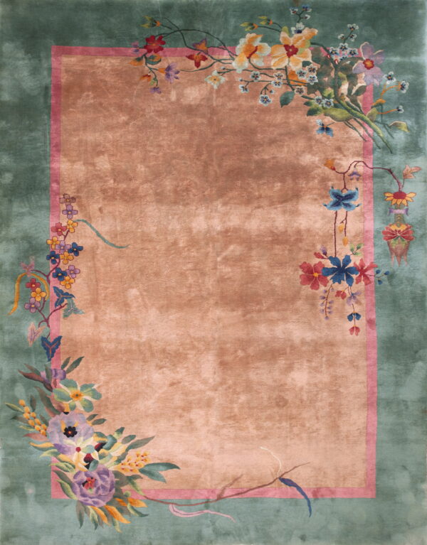 Plush coral rug with green borders featuring bright floral designs and trailing vines.