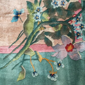 The detailed floral pattern features mauve, blue, and red blooms against green, pink, and beige carved pile.