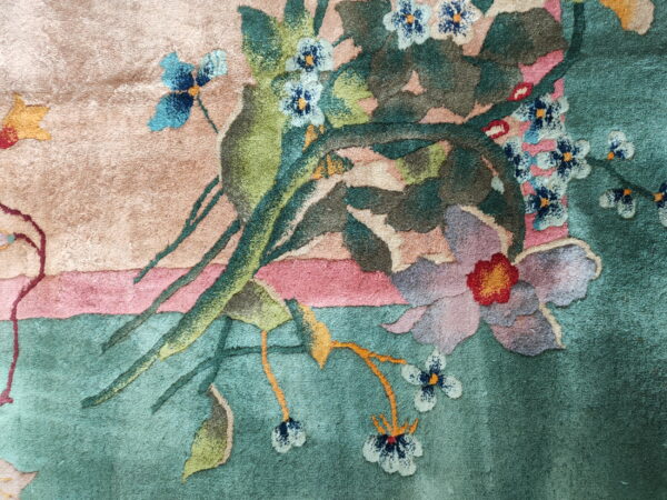 The detailed floral pattern features mauve, blue, and red blooms against green, pink, and beige carved pile.