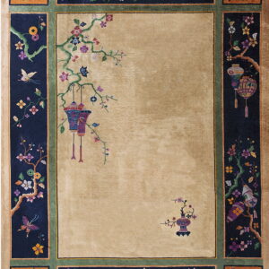 High-pile beige rug with a contrasting navy border decorated with intricate flowering vines and hanging lanterns.